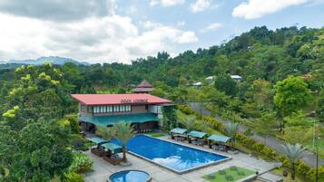 Hotel con piscina, zona de estar exterior y exuberante vegetación.