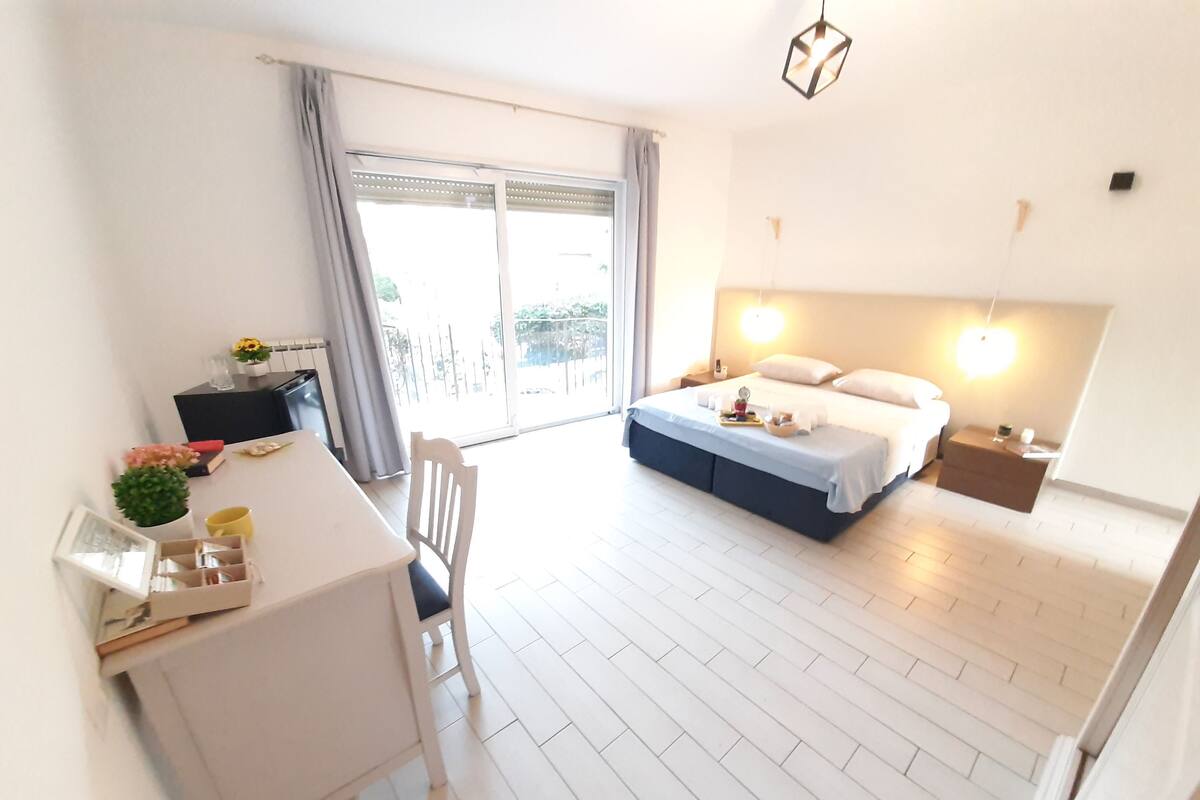 A bedroom with a bed, bedside table, and a desk with a chair.