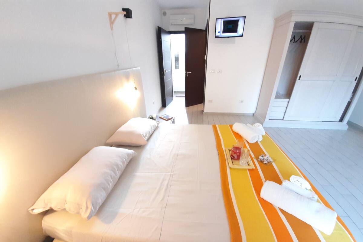 A hotel room with a bed, a TV mounted on the wall, and a door leading to another room.
