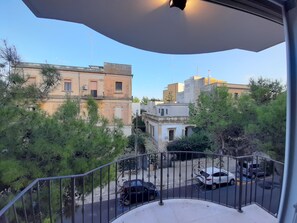 Un balcon donnant sur des voitures garées et des immeubles.