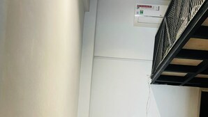 Ein kleiner Wohnbereich mit Holzboden, einem Fernseher, einem Ventilator und einem kleinen Tisch mit Stühlen.