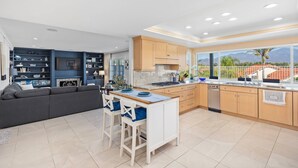 Una cocina moderna con una isla central, armarios de madera y un amplio ventanal con vistas a las montañas.