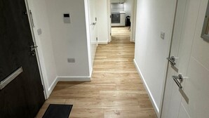 A hallway with wooden flooring leading to a kitchen area. - London - Apartment - Sleeps 2 - Garden - Pool (London)