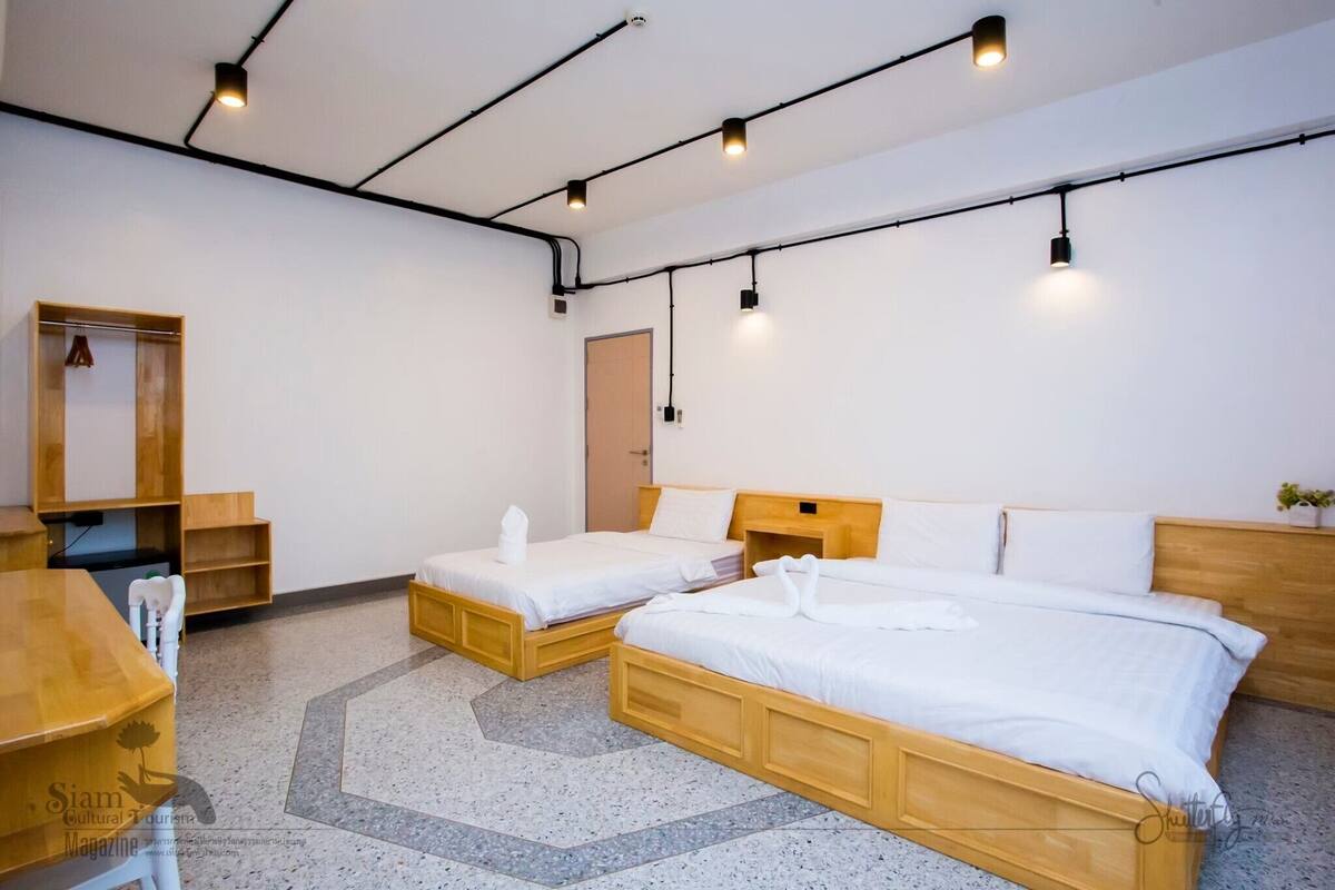 A hotel room with two beds, a wooden desk, a mirror, and a small plant.