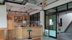 A reception area with a wooden counter, a green stool, and a wooden chair. - Thaphon Residence (Phetchabun)