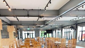 A spacious dining area with wooden tables and chairs, large windows, and modern lighting fixtures. - Thaphon Residence (Phetchabun)