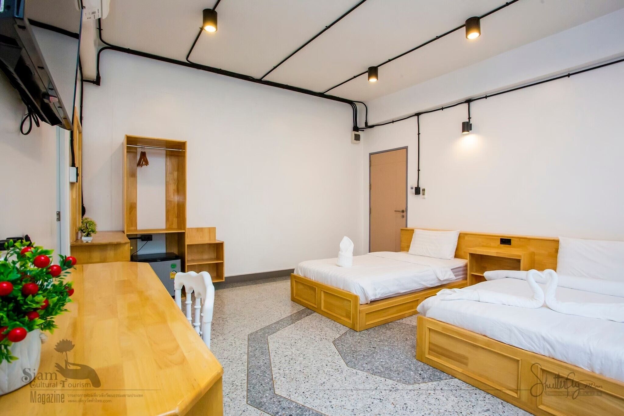 Habitación de hotel con dos camas, un escritorio de madera, una planta pequeña y un armario.