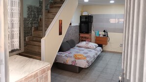 Een slaapkamer met een bed, een televisie, een koffiezetapparaat en een trap.