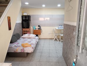 A compact bedroom with a bed, a small desk, a television, and a kitchenette. - G&G small cozy facility,,5 minutes away from the wonderful forest (Napoli)
