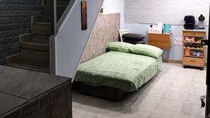 Een slaapkamer met een bed, een bureau, een stoel, een kledingkast en een trap.