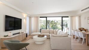 Relax in a spacious living room with a large flat-screen TV, comfortable seating area, and dining space for two.