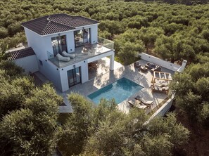 Ein modernes, zweistöckiges Haus mit Pool, umgeben von dichtem Grün.