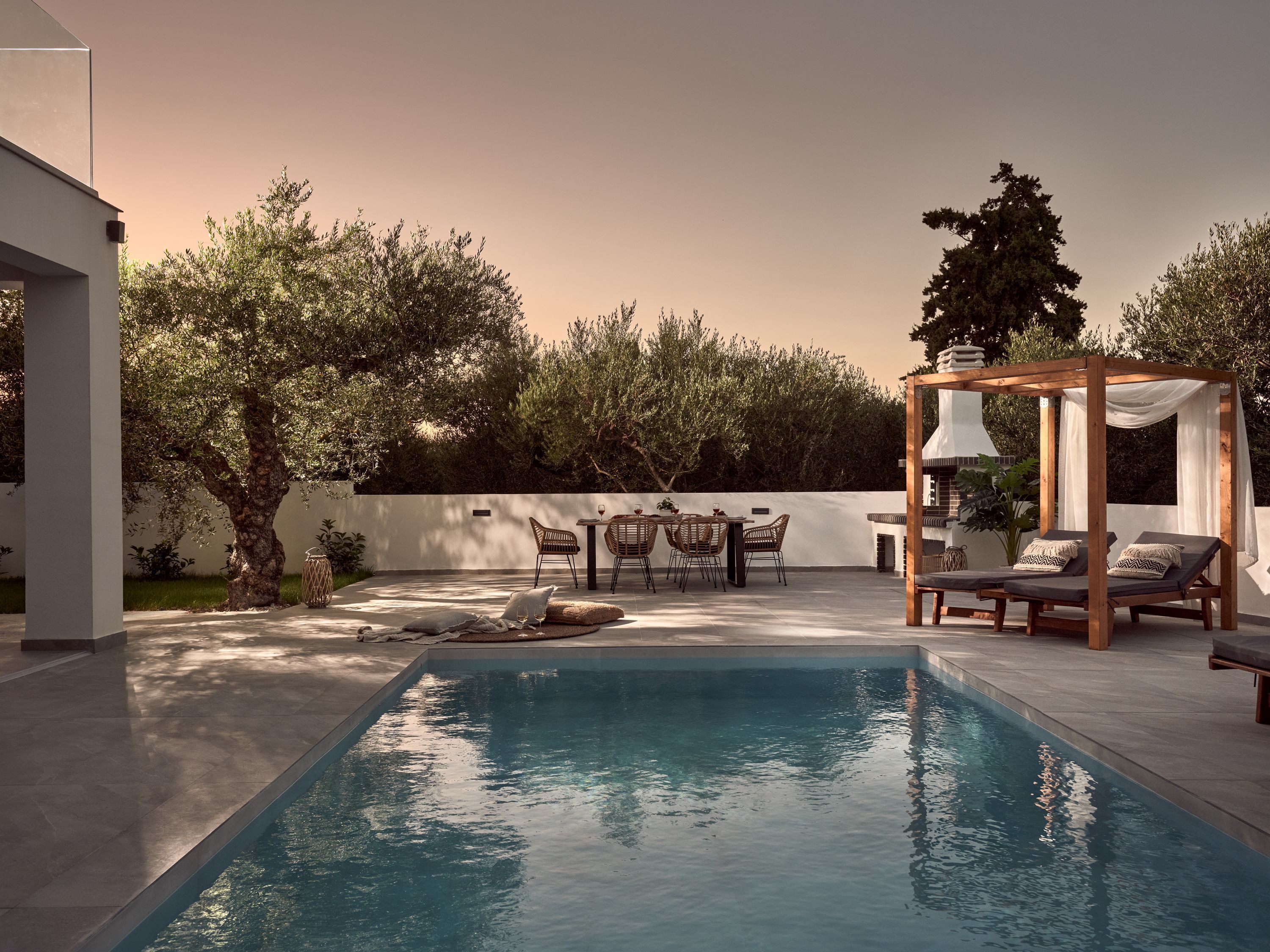 A pool area with a pergola, lounge chairs, and a dining set.