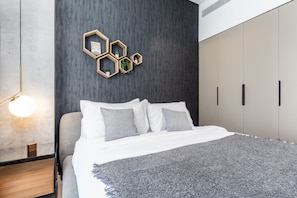 A modern bedroom with a bed, a nightstand, a wall-mounted hexagonal shelf with plants, and a wall-mounted lamp.