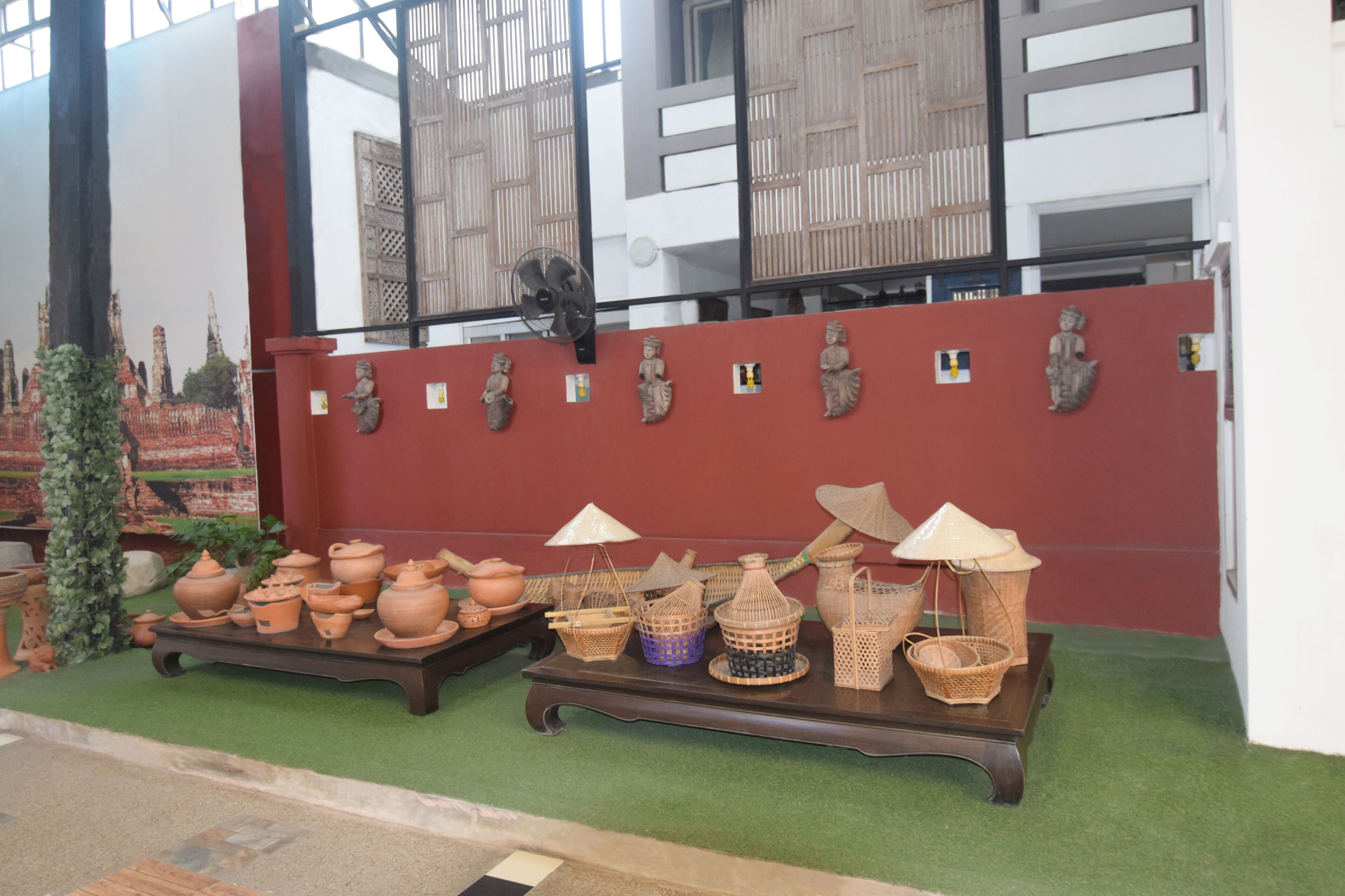A display of traditional pottery and baskets on a wooden table in a museum setting.