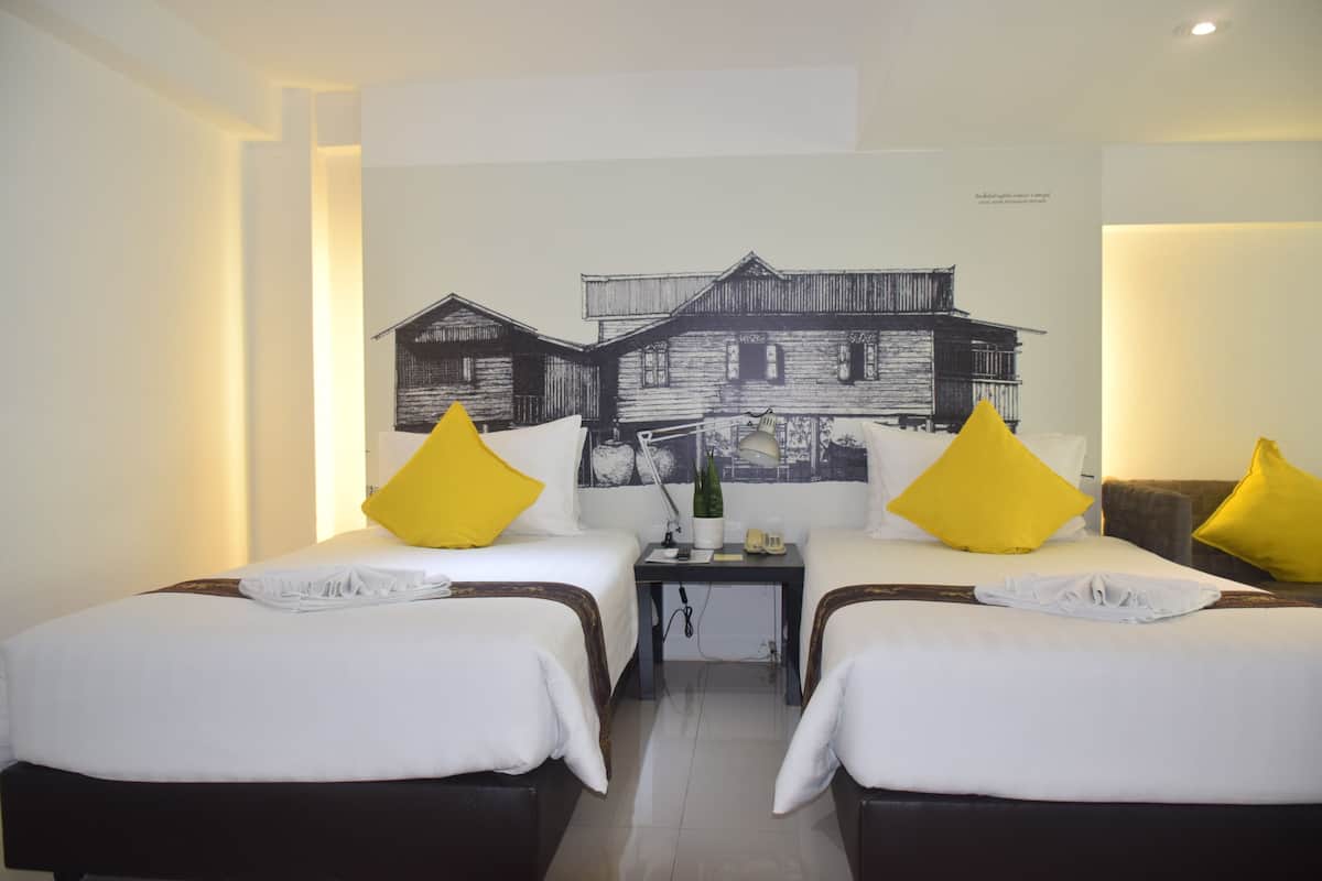 Une chambre d’hôtel avec deux lits, une table de chevet, une lampe et un tableau au mur.