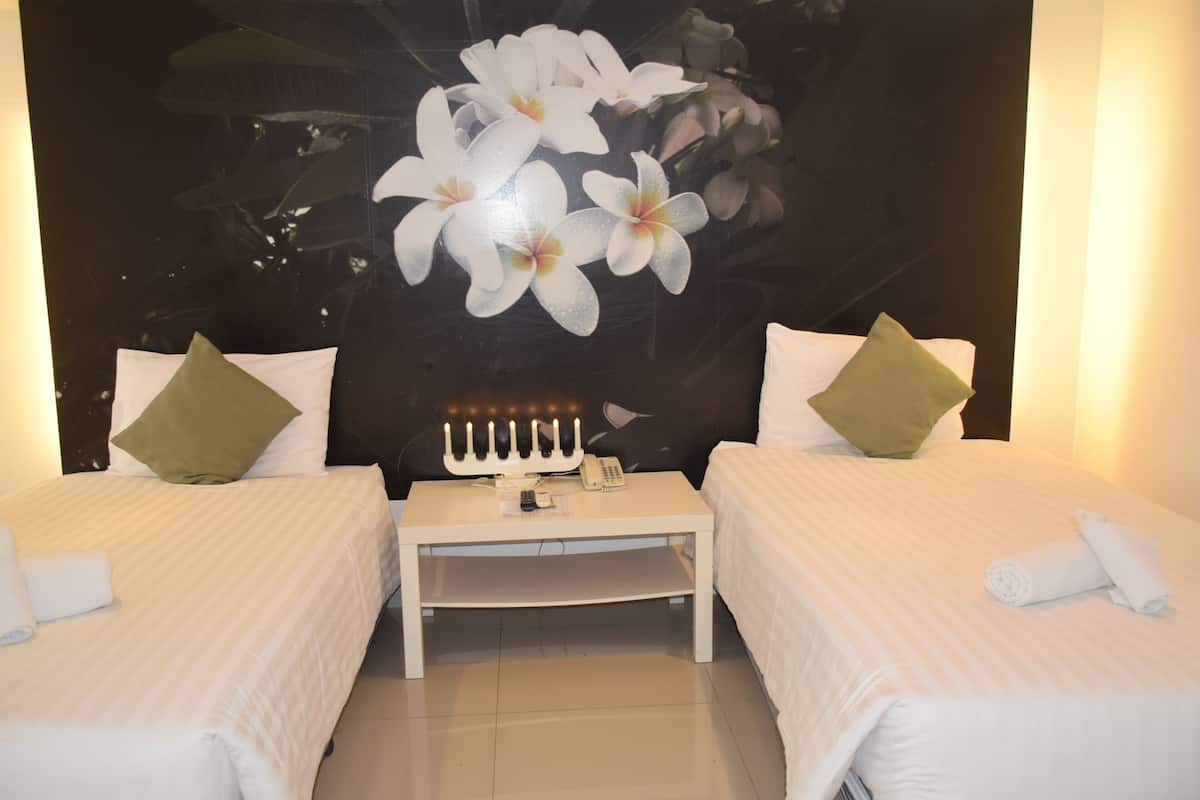 Une chambre d’hôtel avec deux lits, une table de chevet, un téléphone et une tapisserie murale.