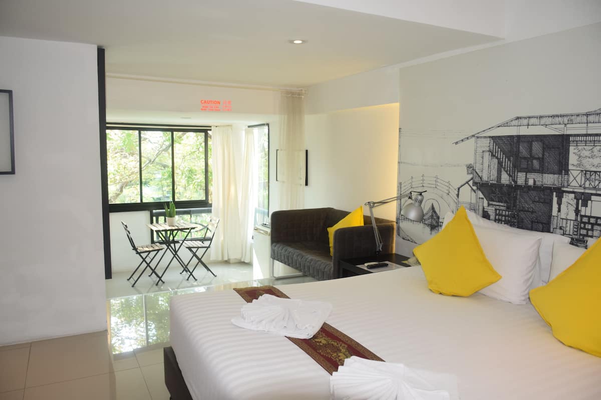 Une chambre d’hôtel avec un grand lit, un bureau, une chaise, un canapé et une fenêtre avec des rideaux.