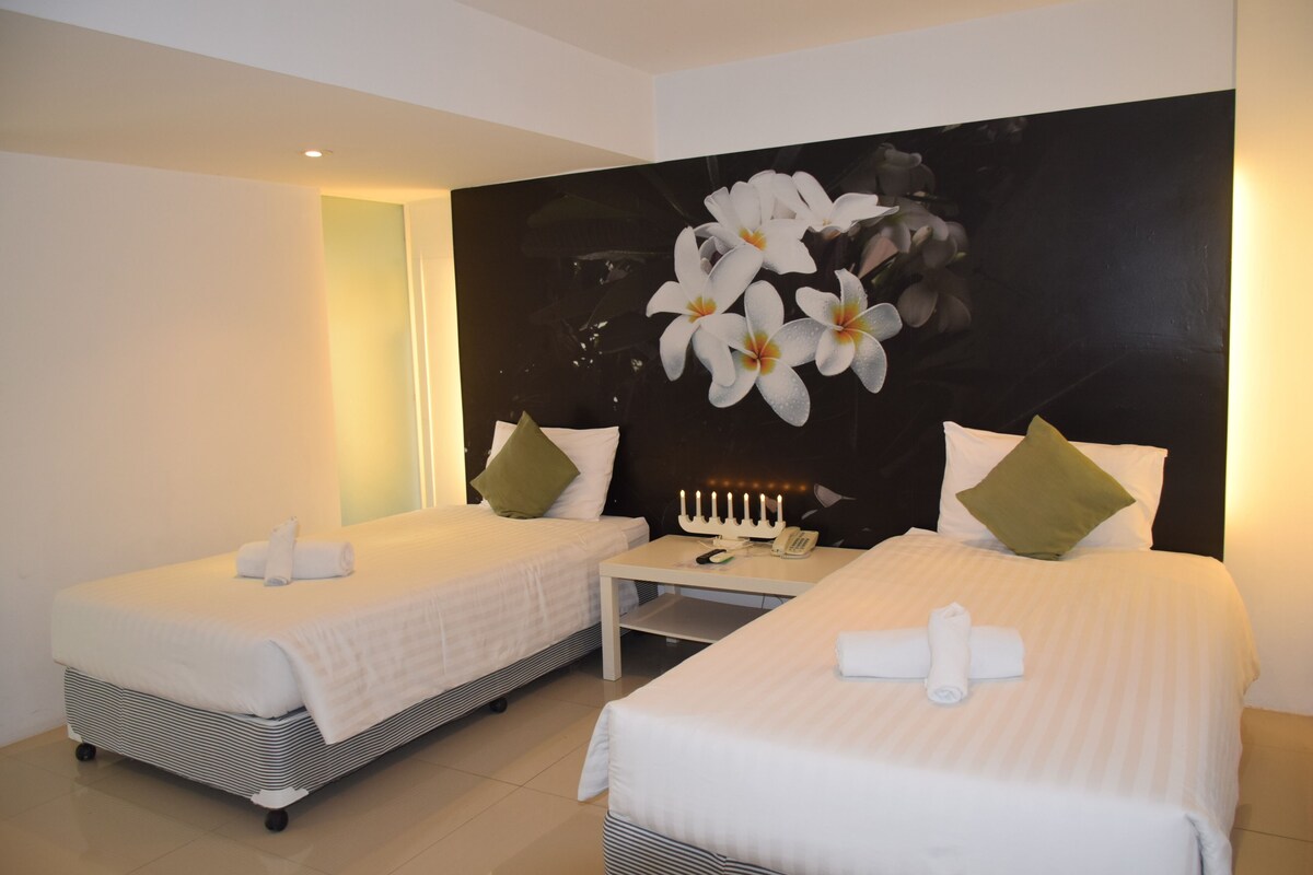 Ein Hotelzimmer mit zwei Betten, einem Nachttisch und einem an der Wand befestigten Telefon.