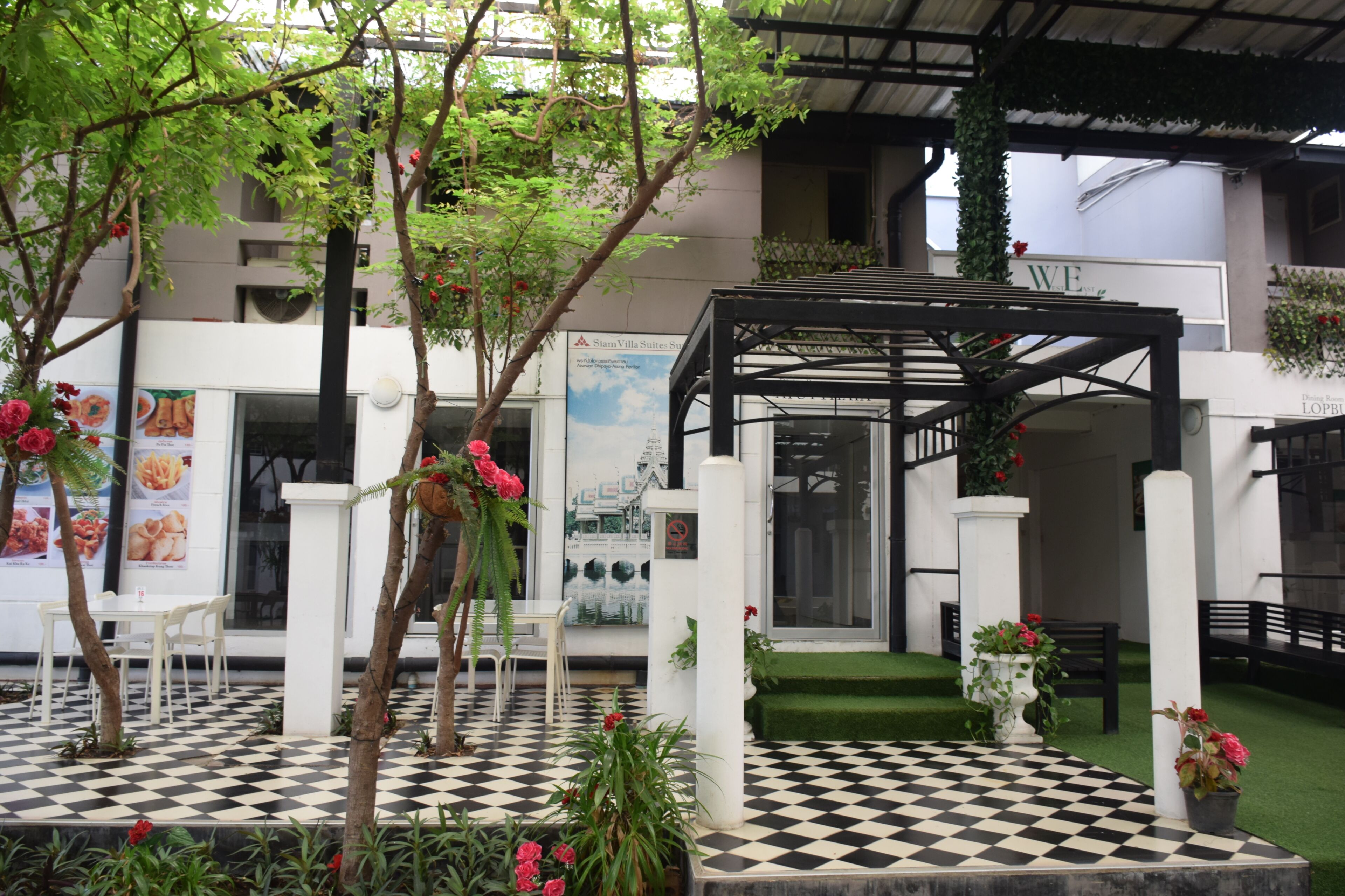 A checkered outdoor area with a pergola, seating, and potted plants.