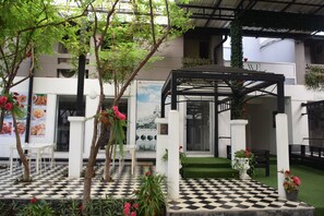 A checkered outdoor area with a pergola, seating, and potted plants. - Siam Villa Suvarnabhumi (Bangkok)