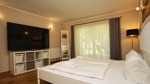 Une chambre d’hôtel moderne dotée d’un grand lit, d’un téléviseur à écran plat, d’un meuble de rangement et d’une fenêtre avec des rideaux.