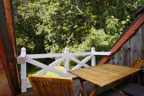 A wooden deck with a white railing, a wooden table, and a chair. - Ruhig und Idyllische Lage im Herzen der Insel Rügen - Gutshaus Silvitz Fewo 03 (Bergen auf Rügen)