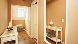 A narrow hallway with wooden floors, white walls, and a ceiling with exposed beams. There are two white doors, one with a small window, and a white console table with a model sailboat. - Ruhig und Idyllische Lage im Herzen der Insel Rügen - Gutshaus Silvitz Fewo 03 (Bergen auf Rügen)