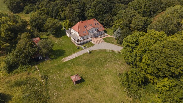 An aerial view of a large house with a red roof, surrounded by lush greenery and fields. - Ruhig und Idyllische Lage im Herzen der Insel Rügen - Gutshaus Silvitz Fewo 03 (Bergen auf Rügen)
