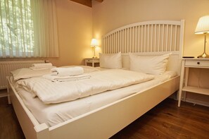 A neatly made bed with white linens and towels, a bedside lamp, and a window with sheer curtains. - Ruhig und Idyllische Lage im Herzen der Insel Rügen - Gutshaus Silvitz Fewo 03 (Bergen auf Rügen)