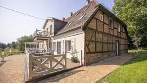 A traditional half-timbered house with a brick facade, a wooden deck, and a white gate. - Ruhig und Idyllische Lage im Herzen der Insel Rügen - Gutshaus Silvitz Fewo 03 (Bergen auf Rügen)