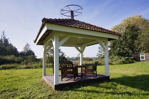 A gazebo with a tiled roof, two wooden chairs, and a table. - Ruhig und Idyllische Lage im Herzen der Insel Rügen - Gutshaus Silvitz Fewo 03 (Bergen auf Rügen)