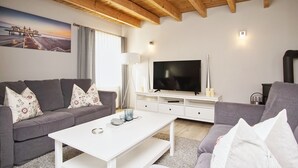 A modern living room with a grey sofa, white coffee table, and a flat-screen TV on a white stand. - Ruhig und Idyllische Lage im Herzen der Insel Rügen - Gutshaus Silvitz Fewo 04 (Bergen auf Rügen)