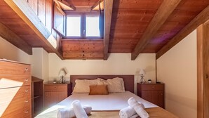 Un dormitorio de madera con una cama grande, dos mesitas de noche y una ventana sobre la cama.