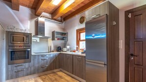 Una cocina moderna con armarios de madera, un refrigerador de acero inoxidable, un horno empotrado y una cafetera.