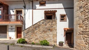Un edificio de dos pisos con una escalera de piedra, un balcón y una ventana pequeña.