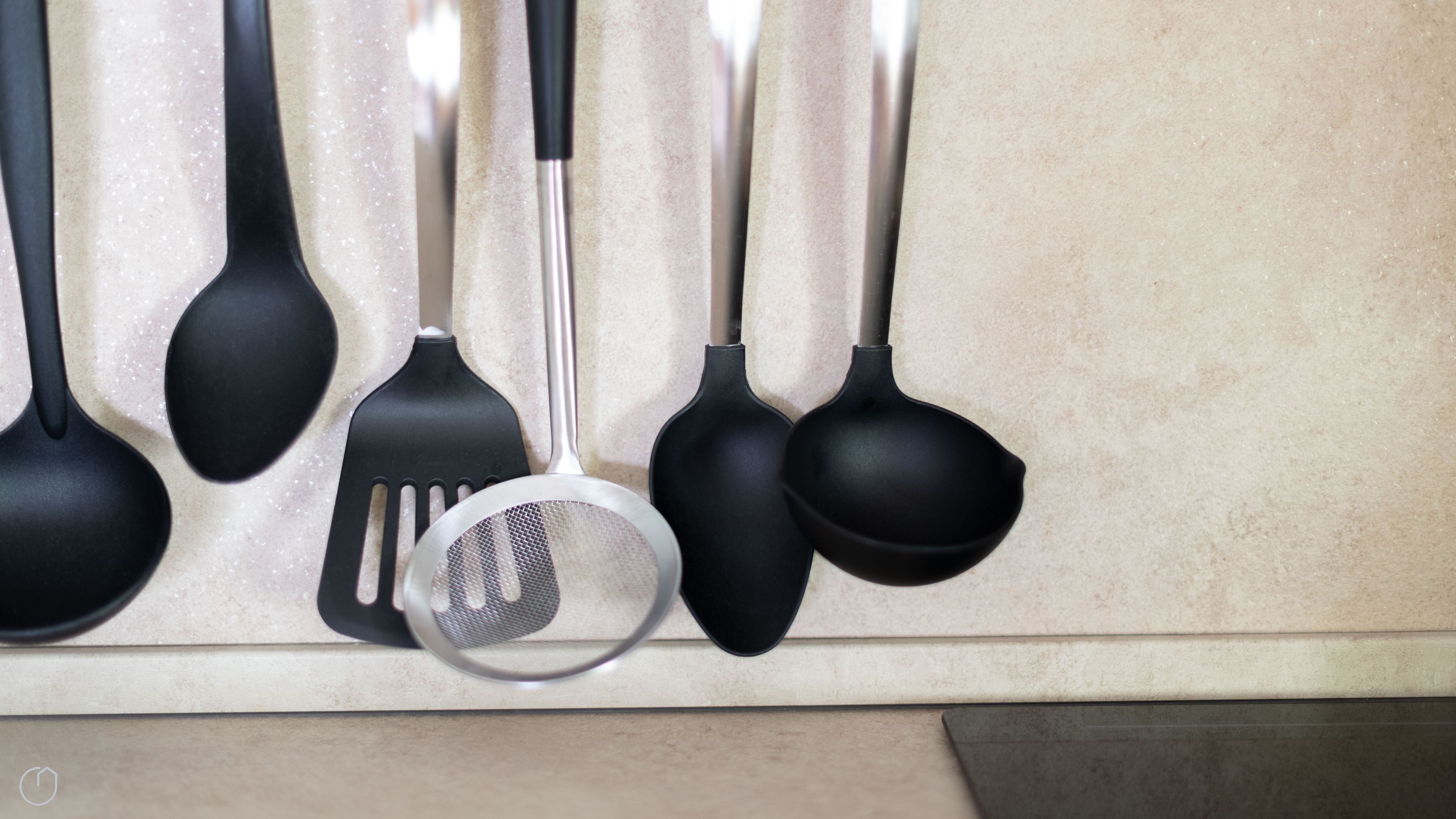 Un porte-ustensiles de cuisine contenant divers ustensiles noirs et en acier inoxydable.