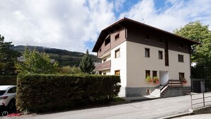 A two-story building with a balcony, a staircase, and a view of a valley. - Leopardi 3 (Bormio)
