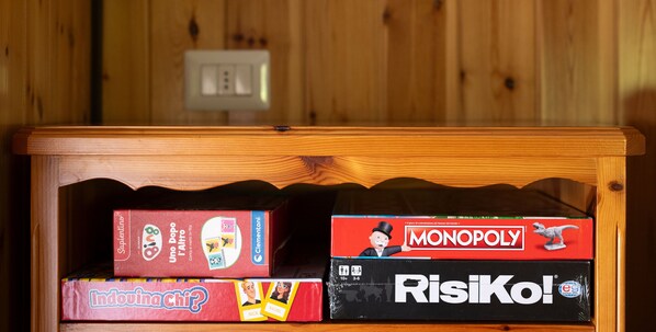 Estante de madeira com quatro jogos de tabuleiro: Uno, Monopoly, Indovina e Risiko.