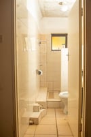 Un baño pequeño con ducha, inodoro y una ventana.