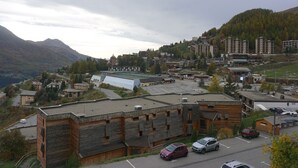 Eine Stadt in den Bergen mit einer Mischung aus modernen und traditionellen Gebäuden, einem Parkplatz und Blick auf die umliegenden Hügel.