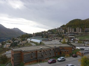 Eine Stadt in den Bergen mit einer Mischung aus modernen und traditionellen Gebäuden, einem Parkplatz und Blick auf die umliegenden Hügel.