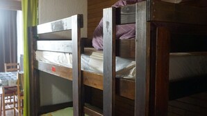 Ein Etagenbett mit Holzrahmen und einer Matratze im oberen Bett.