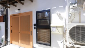 Um edifício com porta de madeira, janela com persianas e aparelho de ar condicionado.