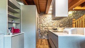 A compact kitchen with a stone wall, wooden beams, and a built-in sink.