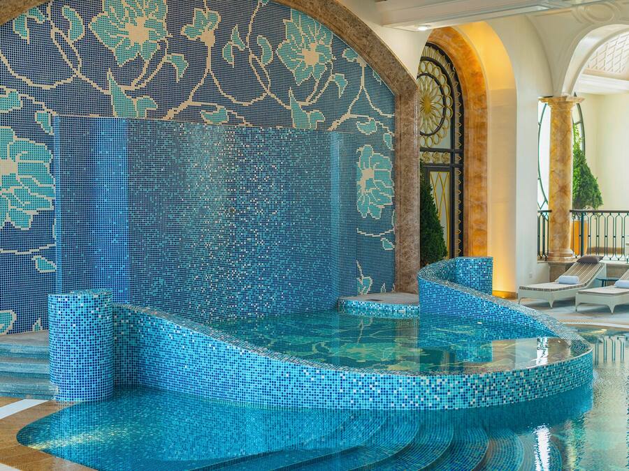 A pool area with mosaic tile walls and steps leading into the water.