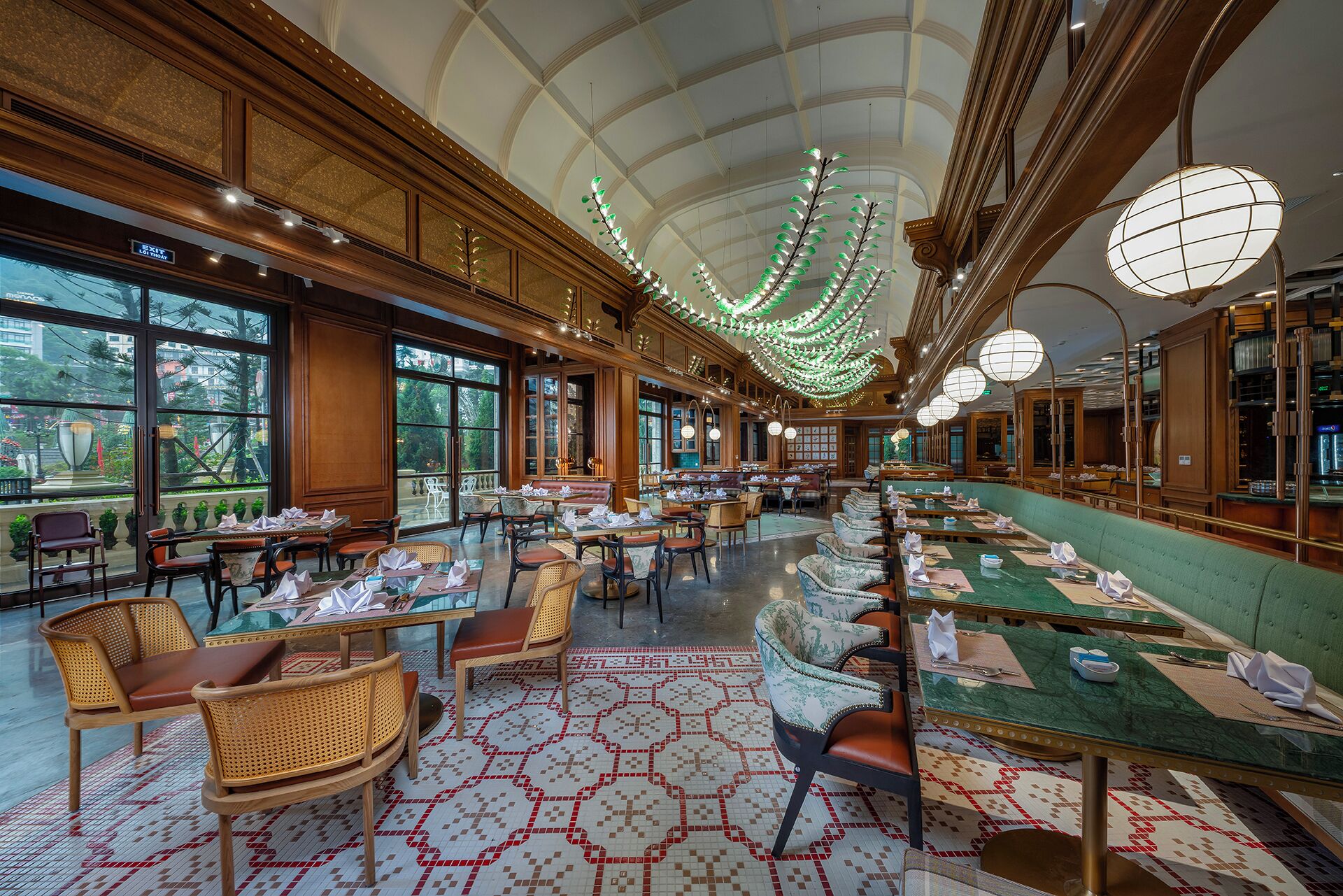 A spacious dining area with high ceilings, chandeliers, and large windows offering views of the outdoors.