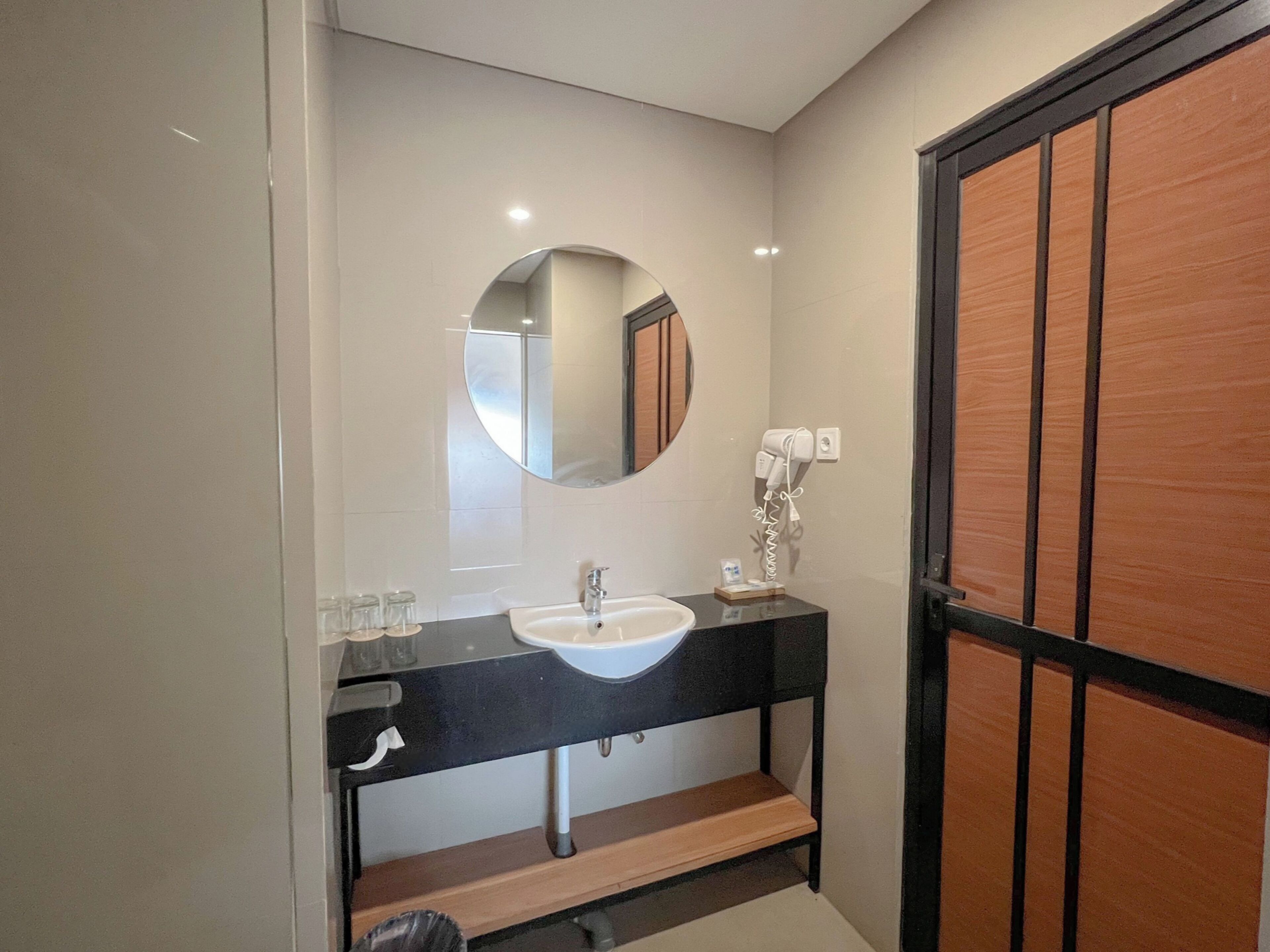 Une salle de bain moderne avec un miroir rond, un lavabo et un porte-serviettes.
