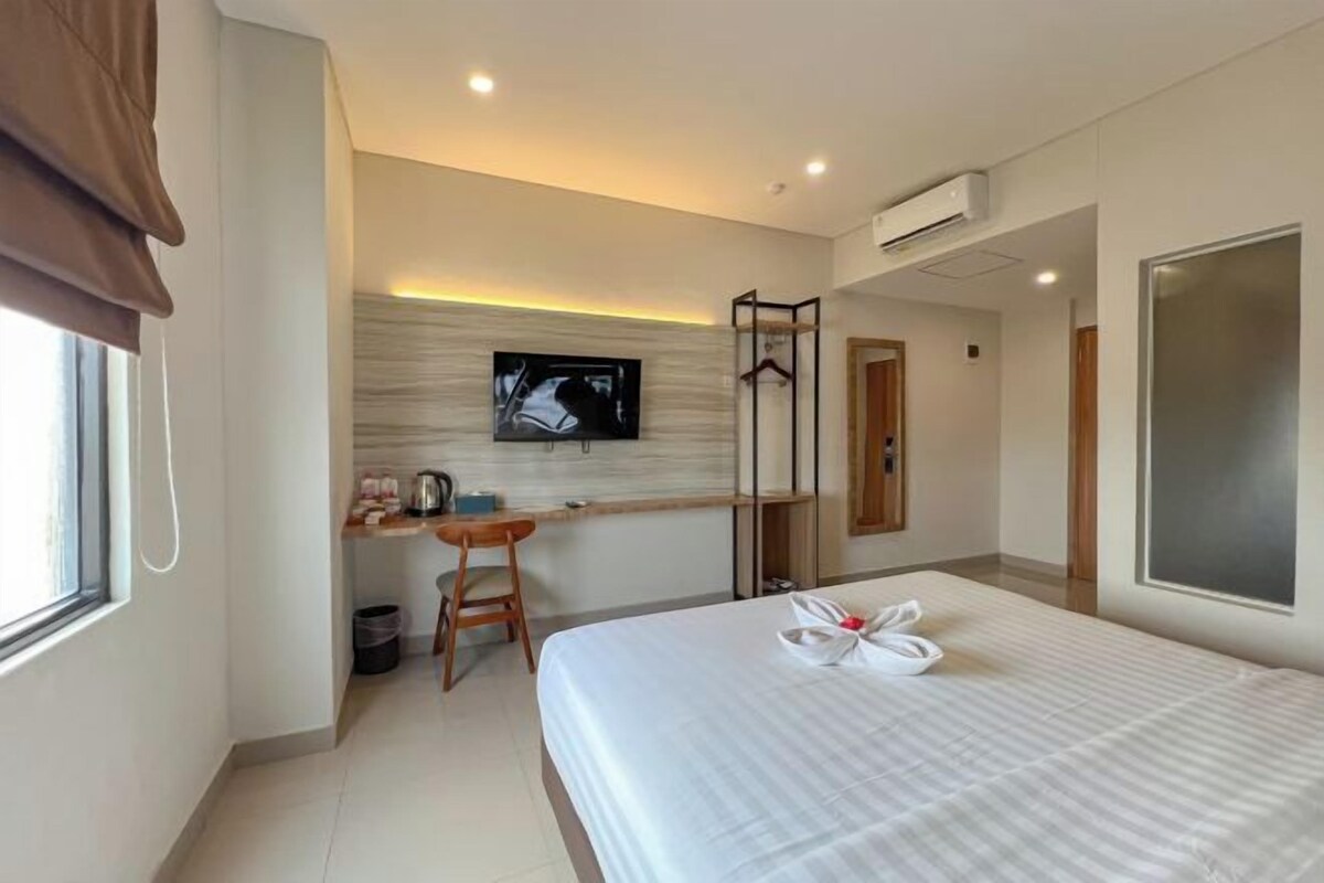 A hotel room with a bed, a desk, a TV, and a wardrobe.