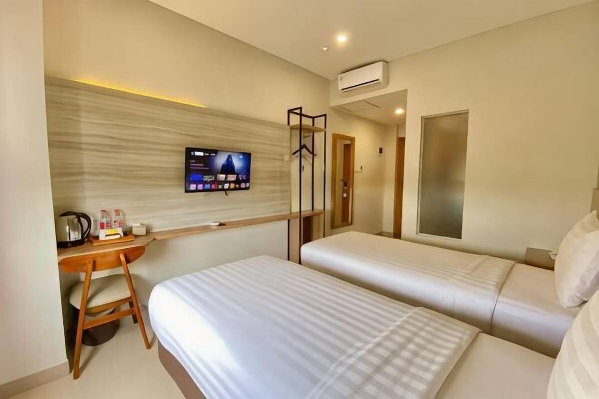 A hotel room with a bed, a desk, a TV, and a wardrobe.